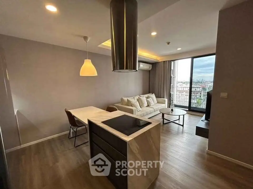 Modern open-plan living room with kitchen island and city view balcony.