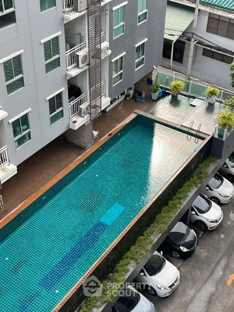 Modern apartment building with swimming pool and parking area view.