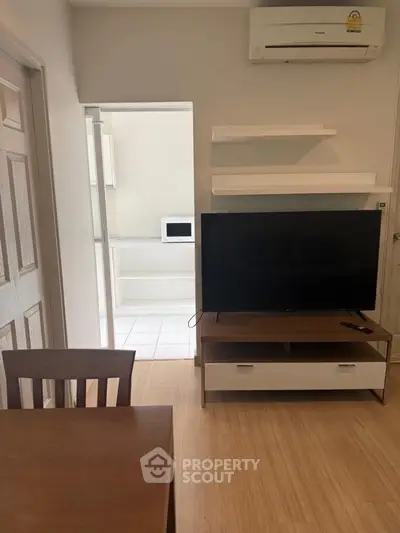 Modern living room with TV, dining table, and air conditioning in a cozy apartment.