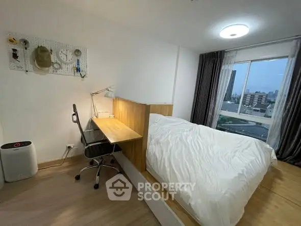 Modern bedroom with study area and city view, featuring a cozy bed and sleek desk.