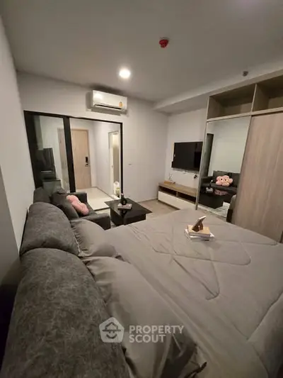 Modern bedroom with cozy gray bedding, stylish decor, and a wall-mounted TV for ultimate relaxation.
