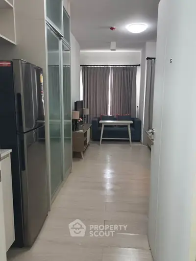 Modern apartment interior with sleek kitchen and cozy living area, featuring stylish furniture and natural light.