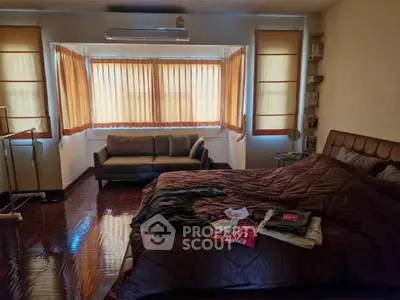 Cozy bedroom with large windows and stylish decor, featuring a comfortable bed and sofa.