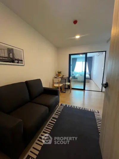 Cozy living room with modern decor and view into a bright bedroom