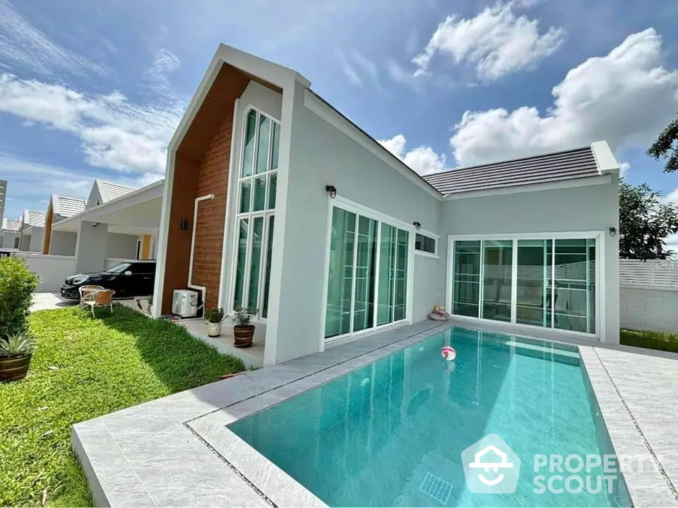 Modern single-story house with private pool and lush green lawn under a clear blue sky.