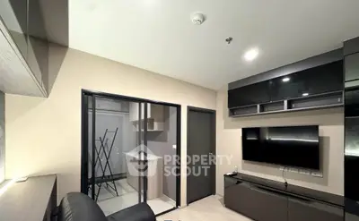Modern living room with sleek black furniture and wall-mounted TV in a contemporary apartment.