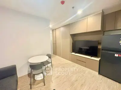 Modern living room with sleek furniture and built-in storage, featuring a flat-screen TV and dining area.