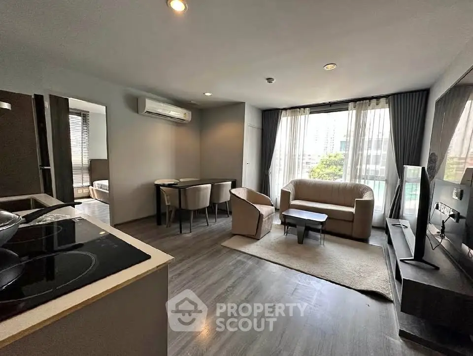 Modern living room with open layout, stylish furniture, and large windows offering city views.