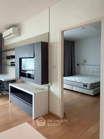 Modern apartment interior with sleek living room and cozy bedroom, featuring wooden flooring and stylish furniture.