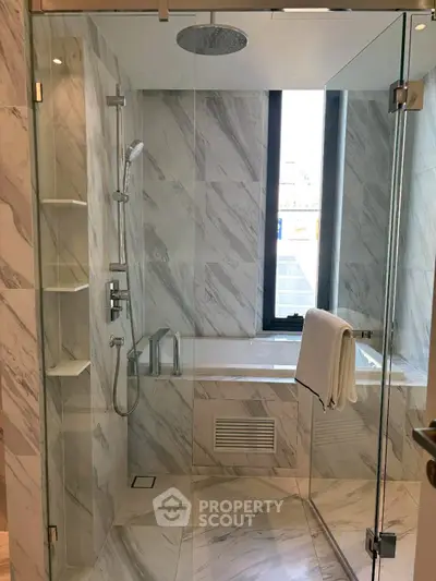 Luxurious marble bathroom with modern shower and bathtub, featuring sleek design and natural light.