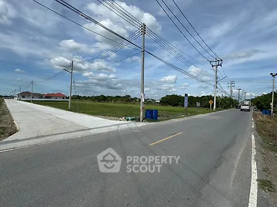 Expansive land plot with road access and clear skies, ideal for development.