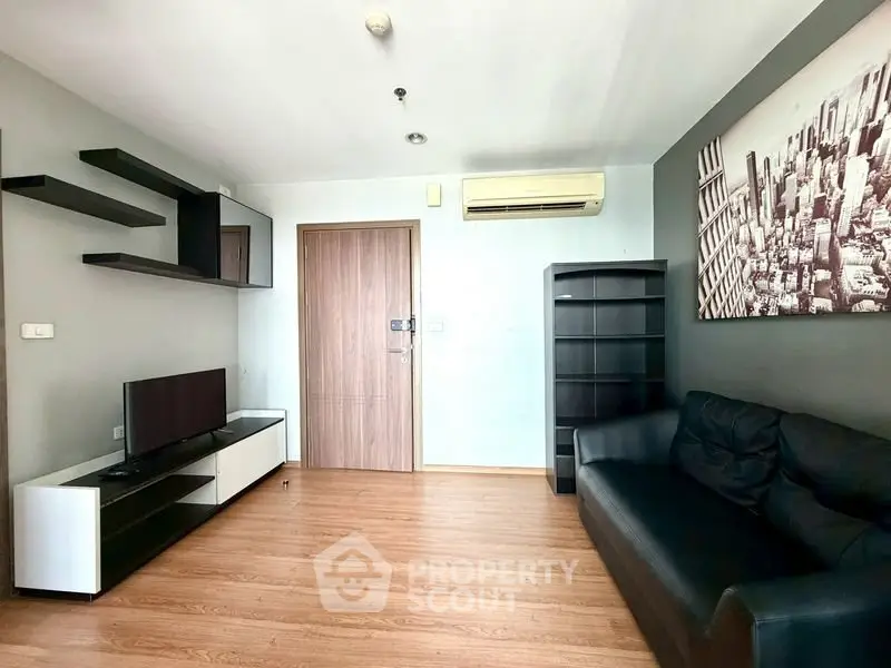Modern living room with sleek furniture and cityscape artwork, featuring a black leather sofa and wall-mounted TV.