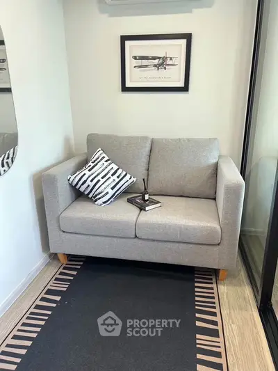 Cozy corner with a stylish gray sofa and decorative pillow, perfect for relaxation or reading.