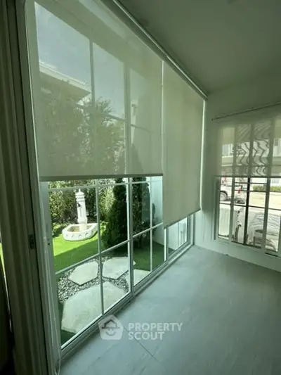 Bright sunroom with large windows overlooking a landscaped garden.