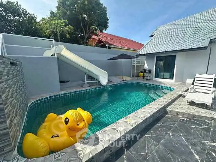 Charming backyard pool with slide and inflatable toy, perfect for family fun and relaxation.