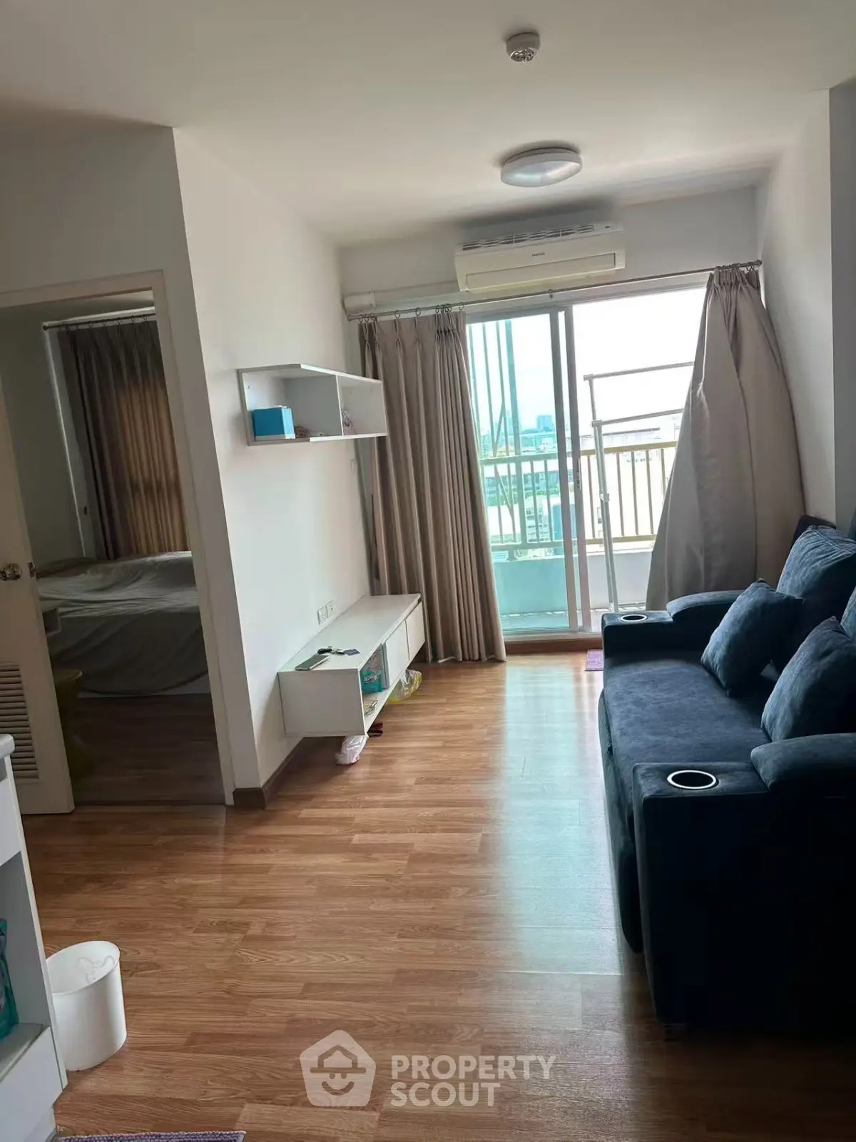 Modern living room with wooden flooring and balcony access in a cozy apartment.
