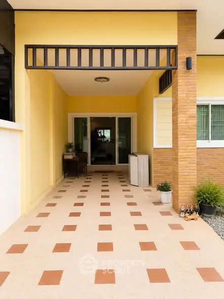 Charming entrance with tiled pathway leading to a cozy home, featuring warm yellow walls and modern design.