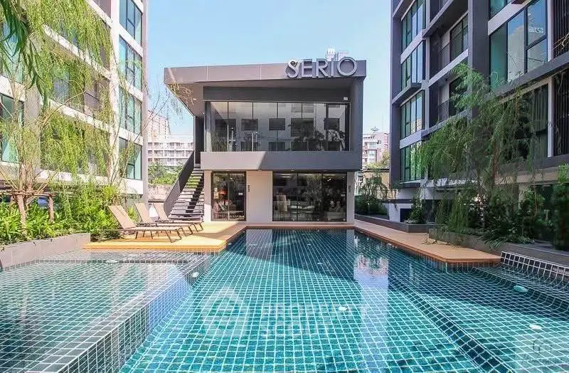 Luxurious modern apartment complex with stunning outdoor pool and lush greenery.