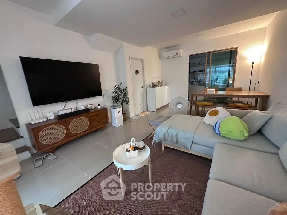 Modern living room with large TV and stylish furniture, perfect for relaxation and entertainment.