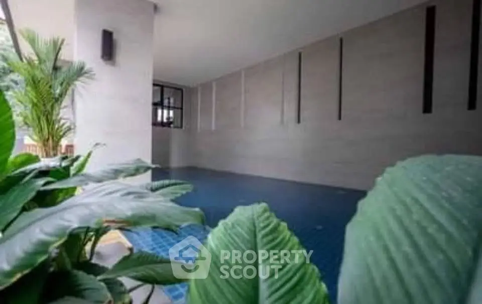 Modern indoor pool area with lush greenery and sleek design elements.