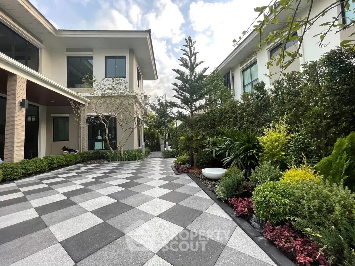 Elegant modern home with lush garden and spacious tiled driveway, perfect for luxury living.