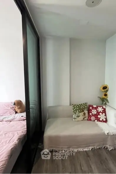 Cozy bedroom with glass partition and charming decor, featuring a comfortable bed and stylish cushions.
