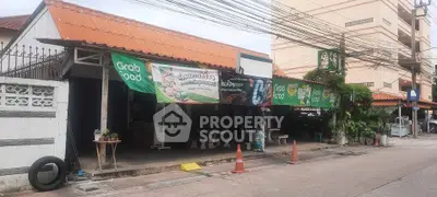 Street view of a local eatery with Grab Food banners and outdoor seating, showcasing vibrant community life.