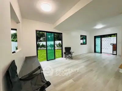 Spacious modern living room with large windows and garden view, perfect for relaxation and entertainment.