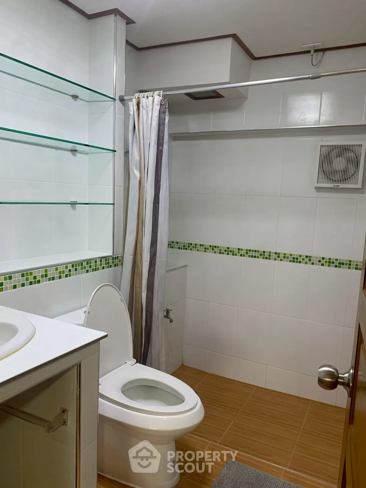 Modern bathroom with glass shelves and tiled floor in a real estate property.