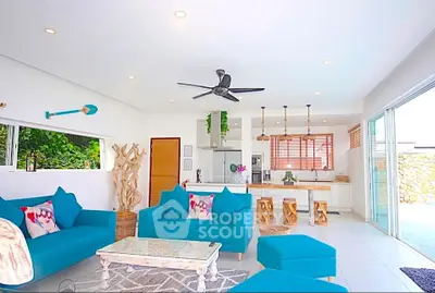 Spacious open-plan living room with vibrant blue sofas and modern kitchen, perfect for entertaining.