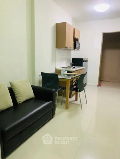 Modern compact kitchen and living area with sleek furniture and appliances in a cozy apartment.