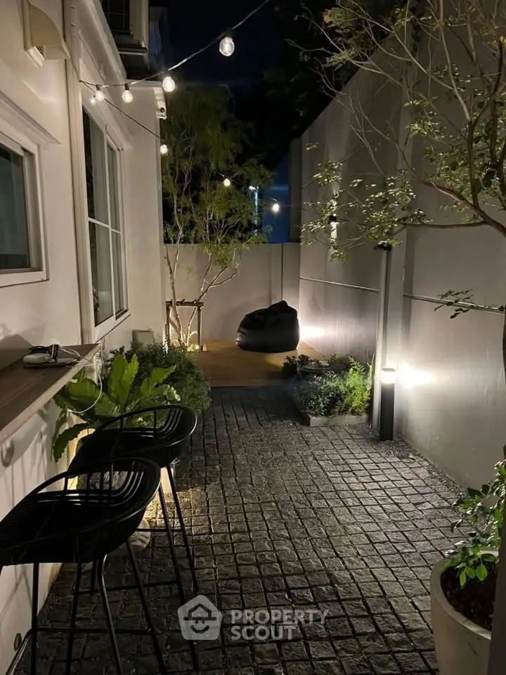 Charming outdoor patio with ambient lighting and modern seating, perfect for evening relaxation.