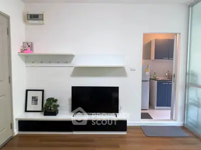 Modern living room with sleek TV setup and view into stylish kitchen