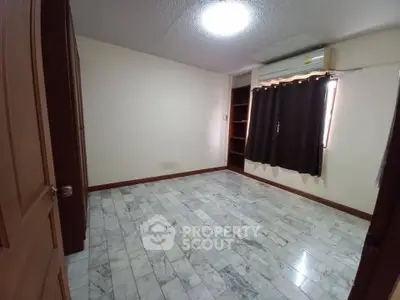 Spacious empty bedroom with marble flooring and air conditioning, ready for customization.
