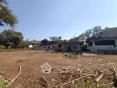 Spacious land plot with potential for development, featuring existing structures and surrounded by greenery.