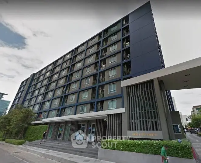 Modern multi-story residential building with sleek design and lush greenery in urban setting.