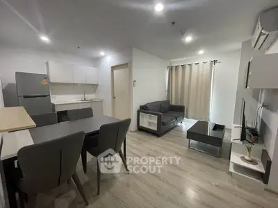 Modern open-plan living room with kitchen, featuring sleek furniture and neutral tones.
