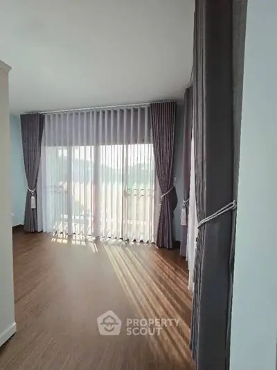 Spacious room with large windows and elegant curtains, perfect for natural light lovers.