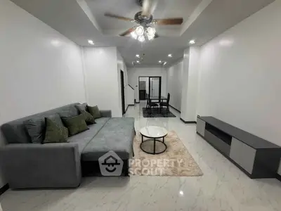 Spacious modern living room with elegant gray sofa and chic dining area, perfect for entertaining.