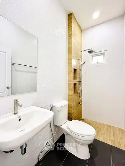 Modern bathroom with sleek fixtures and wooden accent shower area.