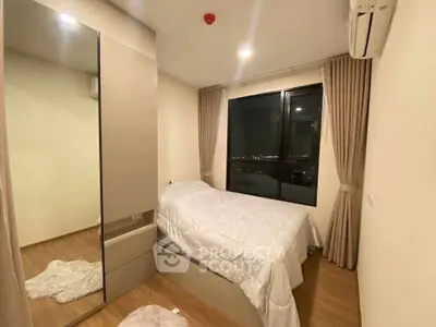 Cozy bedroom with modern decor and city view, featuring a large mirror and air conditioning.