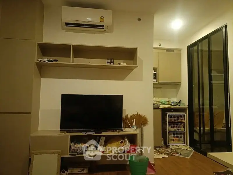 Cozy living room with modern TV setup and adjacent kitchen area