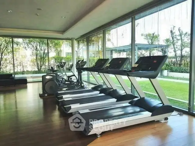 Spacious gym with modern treadmills and garden view in luxury property.