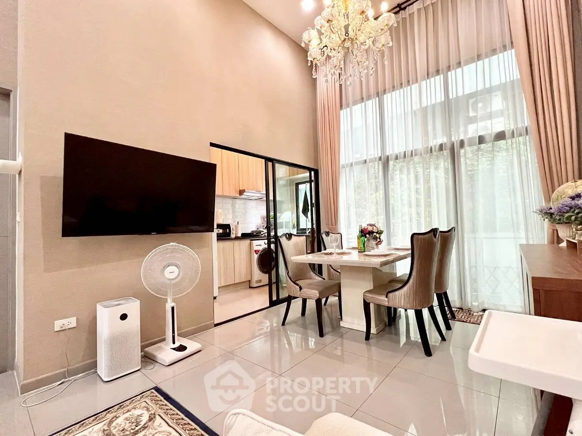 Luxurious high-ceiling living room with elegant chandelier and modern kitchen access