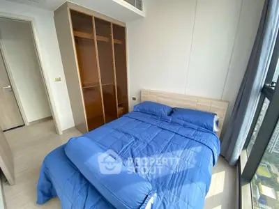 Modern bedroom with blue bedding and large window offering city view
