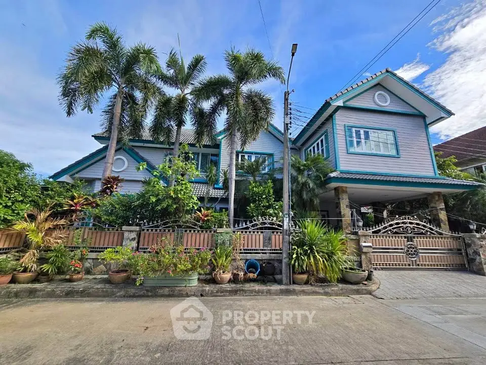Charming two-story house with lush garden and palm trees, featuring a spacious driveway and elegant exterior design.