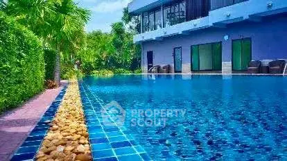 Luxurious poolside view with modern building and lush greenery