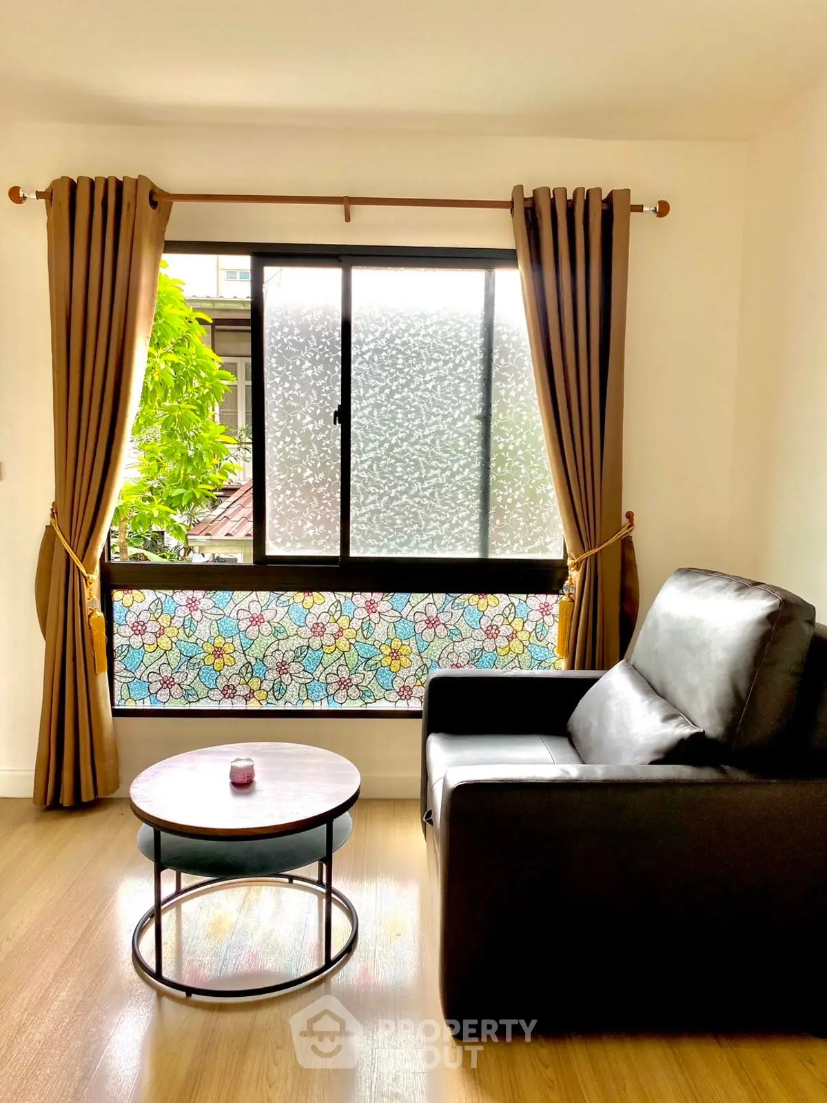 Cozy living room with leather sofa and floral window design, perfect for relaxation.