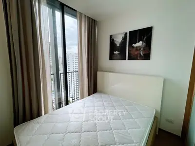 Modern bedroom with large window and stylish decor in urban apartment.