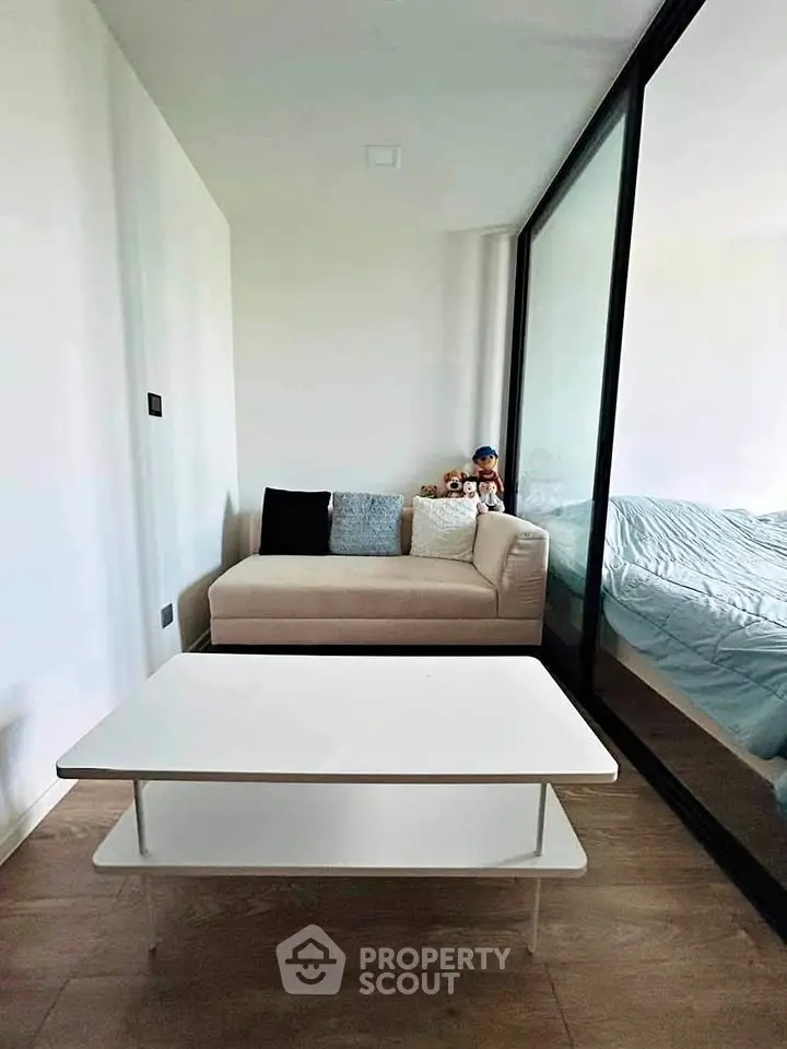 Modern living room with cozy sofa and glass partition leading to bedroom, perfect for urban living.